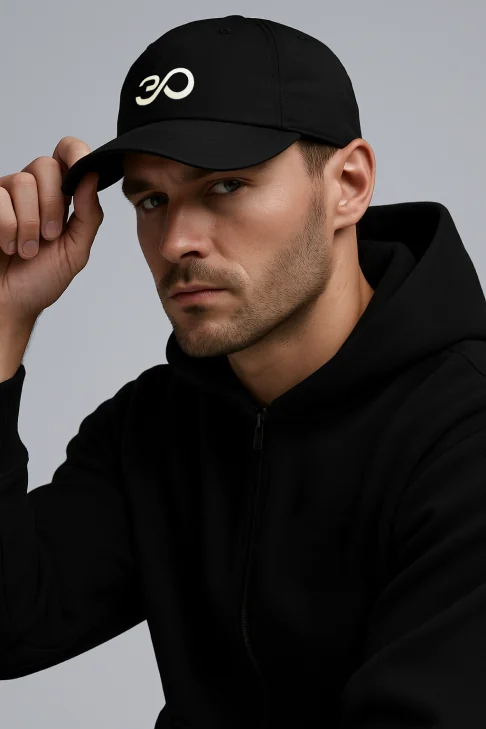 A man in a black hoodie adjusting a black cap with the Feel30 symbol.