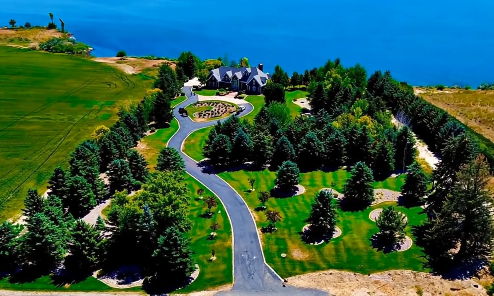 Aerial view of a winding drive through landscaped grounds above a lake.