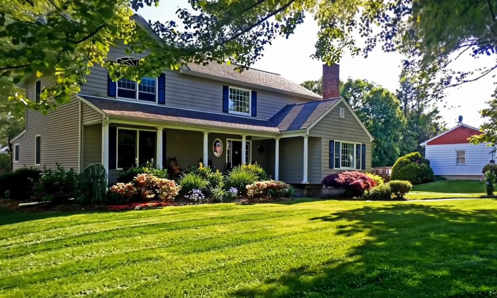 A freshly striped lawn in front of a two-story home with flowering beds.