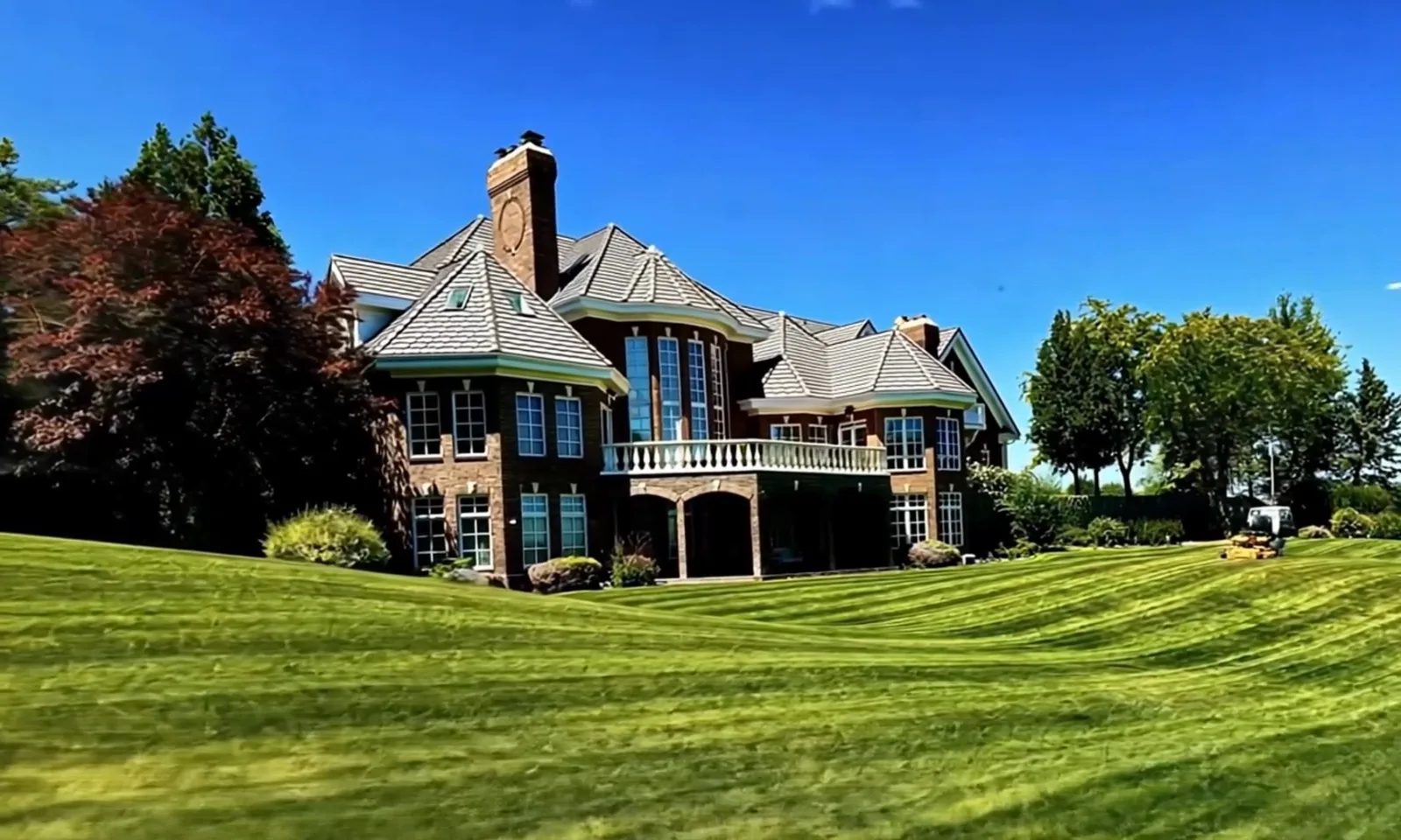 A large stone-and-shingle home above a striped lawn.