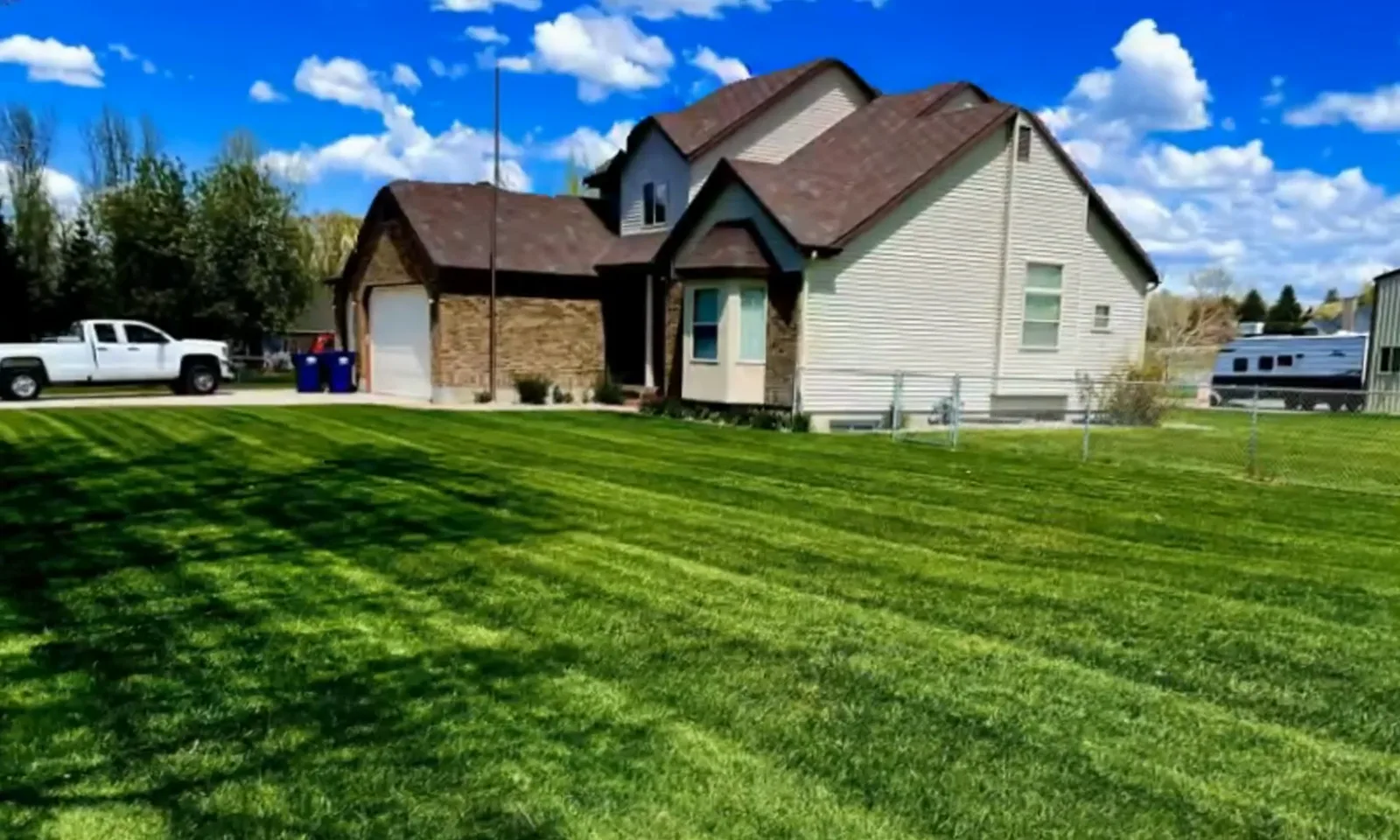 A crisp green lawn in front of a new home with a Kendell truck in the drive.