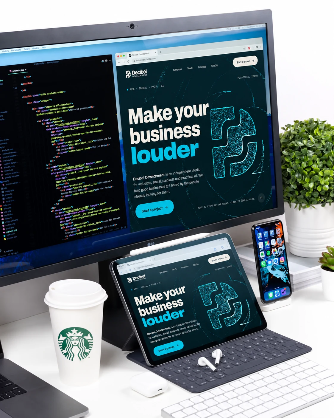 A desk setup with a monitor, iPad and phone showing the Decibel Development site, next to code, a coffee and plants.